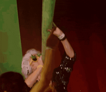 a woman in a sequined dress is holding a clock and a green light