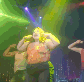 a woman is singing into a microphone while dancing on stage