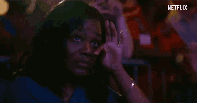 a woman is covering her face with her hand while sitting in a crowd .