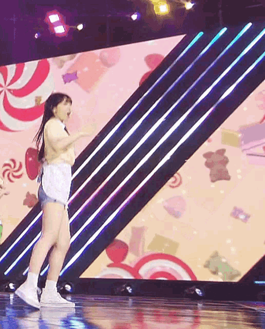 a woman is dancing on a stage in front of a large screen