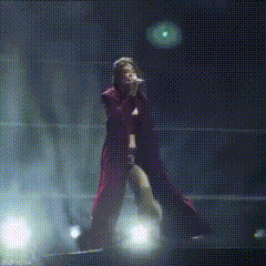 a woman is singing into a microphone on stage