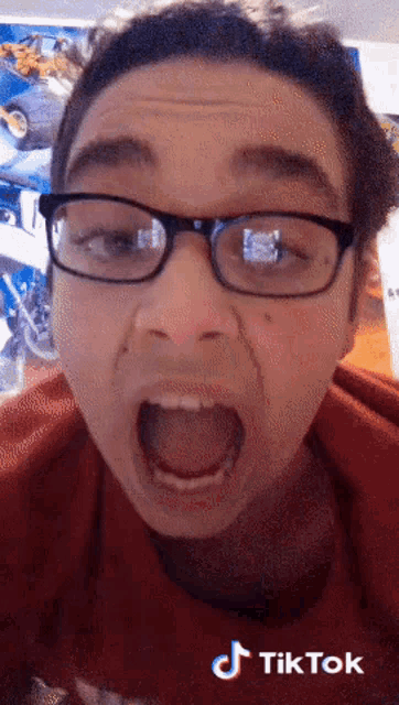 a man wearing glasses and a red shirt is making a funny face with a tiktok watermark