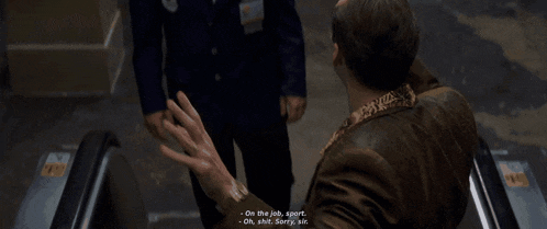 a man in a blue suit talking to another man in a brown jacket