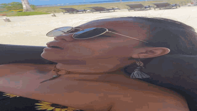 a woman wearing sunglasses and a choker is laying on a beach