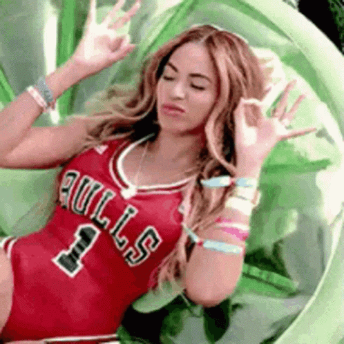 a woman is wearing a bulls jersey and making a funny face while sitting in a chair .