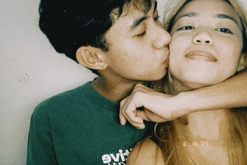 a man kisses a woman on the cheek while wearing a green shirt that says evi on it