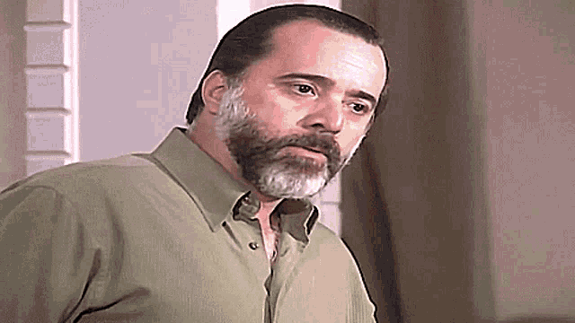 a man with a beard and a green shirt is looking at the camera