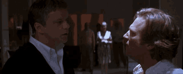 two men are looking at each other with a woman standing in the background