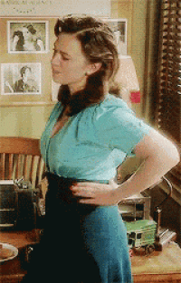 a woman in a blue dress is standing in front of a window with her hands on her hips