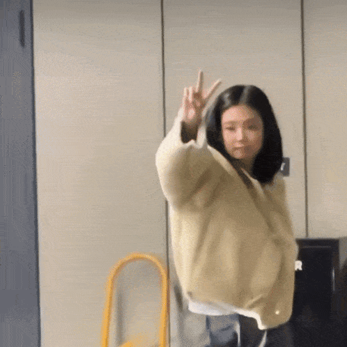 a woman giving a peace sign with her hand