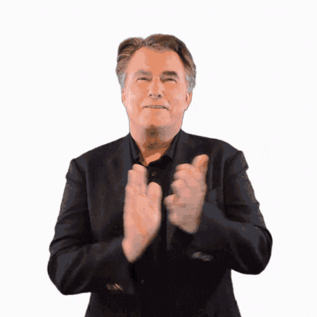 a man in a suit is clapping his hands and smiling