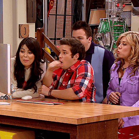 a group of people are sitting at a table looking at a laptop