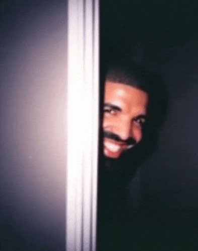 a man with a beard and mustache is peeking out from behind a door .
