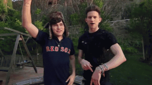 a man wearing a red sox shirt stands next to another man wearing a hat