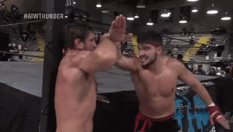 two wrestlers are giving each other a high five in a ring
