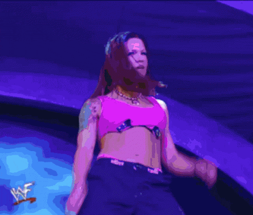a woman in a pink top and black shorts is dancing on a stage