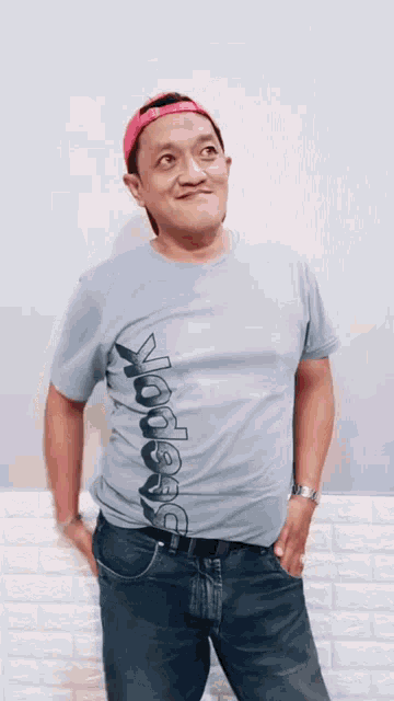 a man wearing a reebok t-shirt and a pink baseball cap is giving the middle finger .