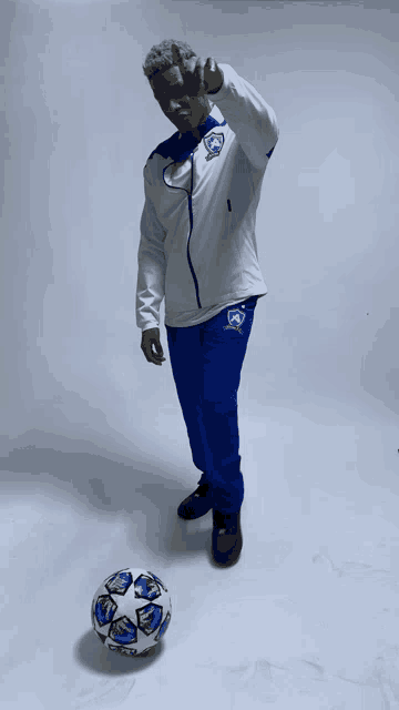 a man standing next to a soccer ball giving the peace sign