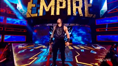 roman reigns is standing on a stage in front of the empire sign