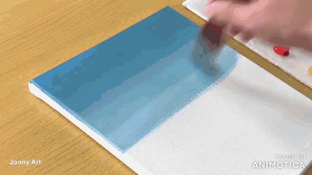 a person is painting a blue and white painting on a canvas