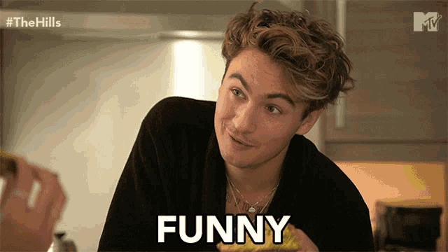 a man in a black robe says funny in front of a tv screen