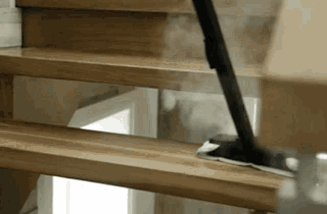 a person is using a mop to clean a wooden staircase