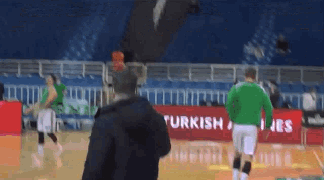 a man stands on a basketball court in front of a turkish airlines banner