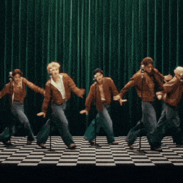 a group of men are singing into microphones on a checkered floor