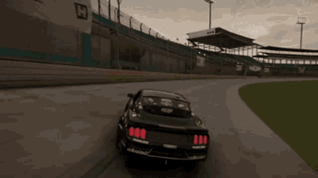 a black car is driving on a race track with a welders logo on the back