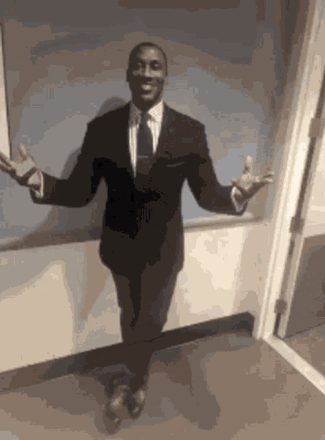 a man in a suit and tie is standing in a hallway with his arms outstretched .