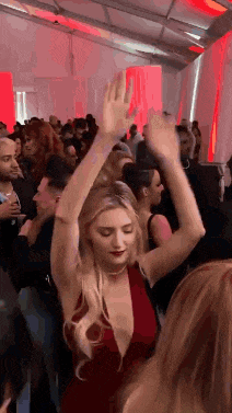 a woman in a red dress is dancing in a crowd .