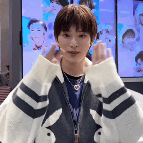 a young man in a bunny sweater is making a heart shape with his hands .