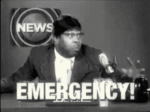 a man in a suit and tie is talking into a microphone in front of a news sign that says emergency .