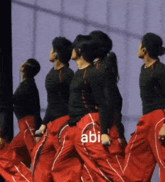 a group of people are dancing on a stage and the word abi is on the back of their pants