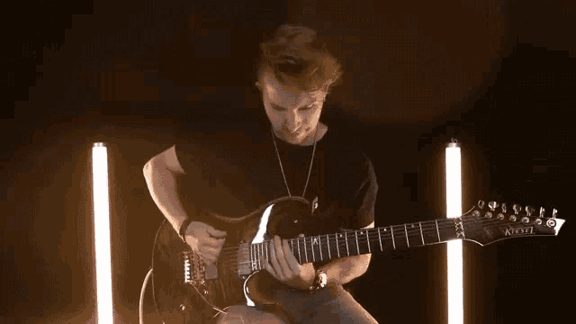 a young man is playing a guitar in a dark room .