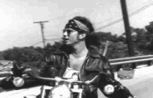 a man wearing a bandana rides a motorcycle