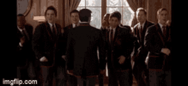a group of men in suits and ties are standing in front of a window and singing .