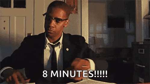 a man in a suit and tie is sitting at a desk and says 8 minutes