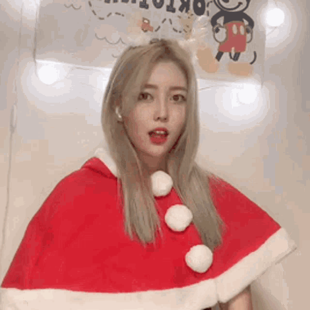 a woman is wearing a santa cape and a mickey mouse costume .