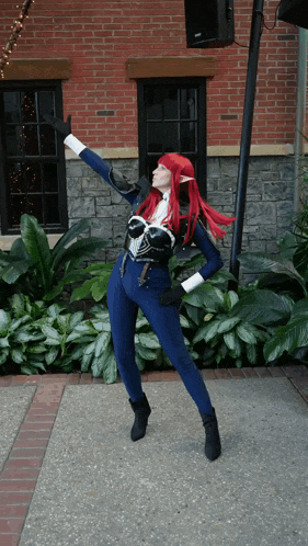 a woman with red hair is standing in front of a brick wall
