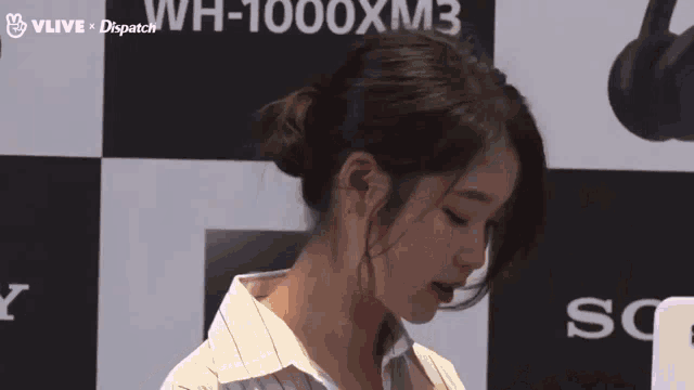 a woman stands in front of a wall that says wh-1000xm3 on it