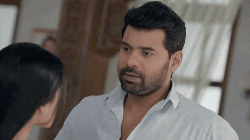a man in a white shirt looks at a woman