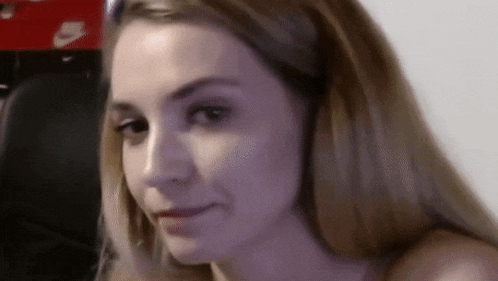 a close up of a woman 's face with a blurred background looking at the camera .