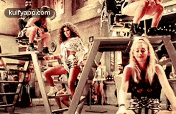 a group of women are dancing on a stage in a room .