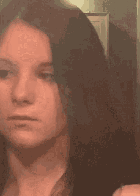 a woman is taking a selfie in front of a mirror and looking at herself .