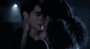 a man and a woman kissing in the rain at night