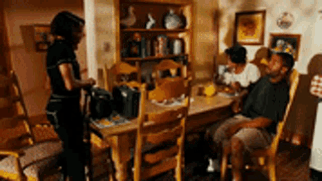 a group of people are sitting at a table in a dining room