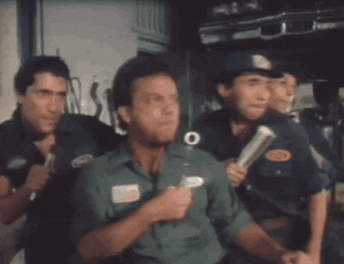 a group of men are standing in a room and one man is blowing bubbles