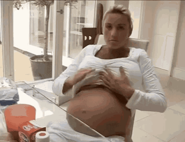 a pregnant woman sitting at a table with a box of oatmeal