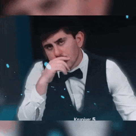 a man in a suit and bow tie is covering his mouth with his hand .